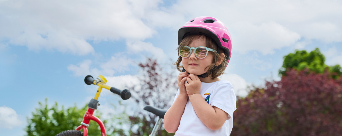 Kind mit KED Kinderhelm und Fahrradbrille auf dem Laufrad